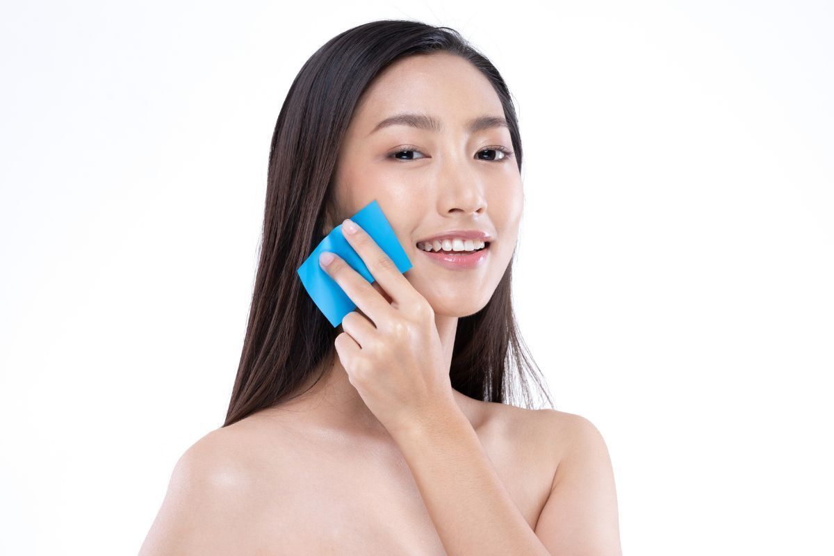 cách trị mụn ẩn cô gái cầm giấy thấm dầu màu xanh dương áp lên má