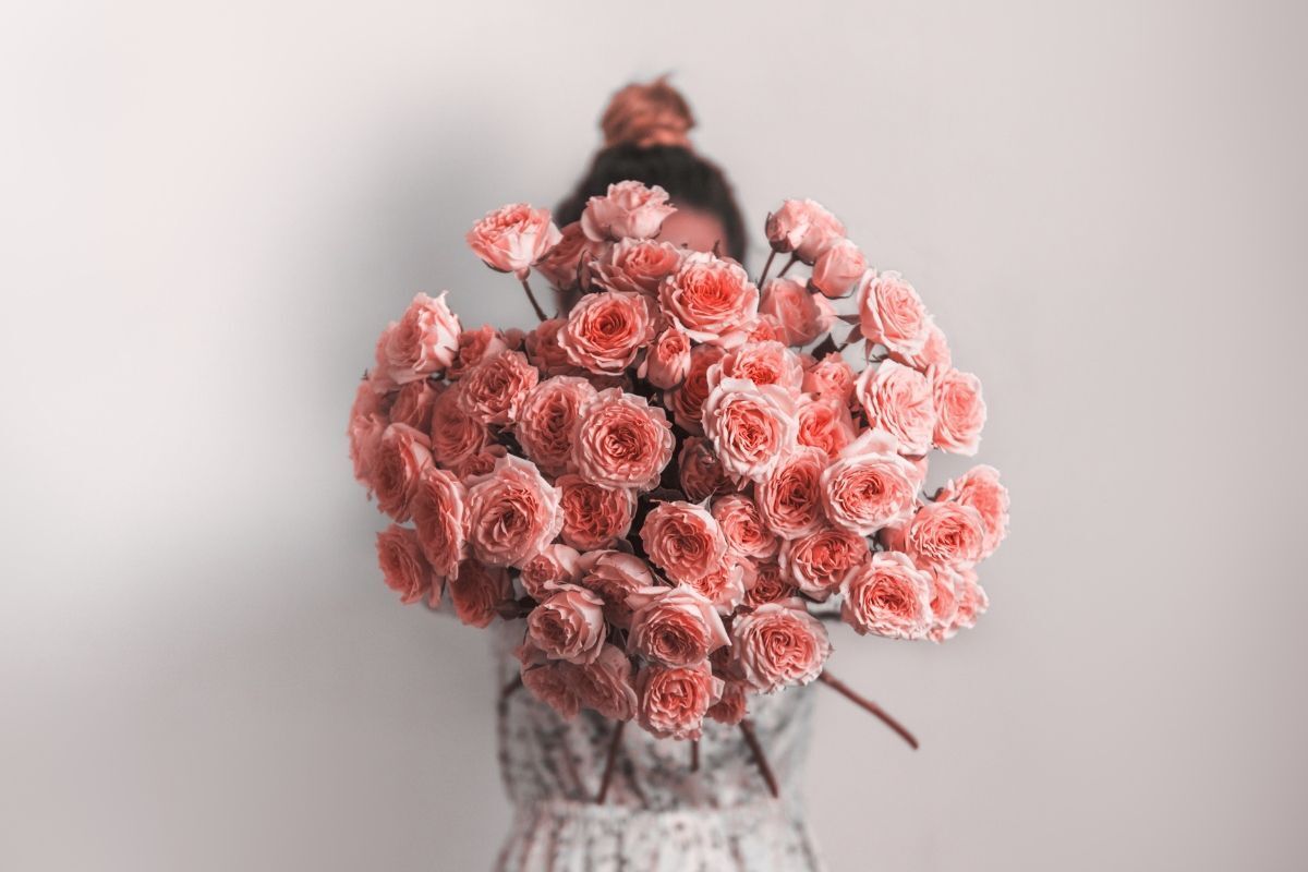 Mẫu hoa 20/10 đẹp cô gái cầm bó hoa hồng che mặt