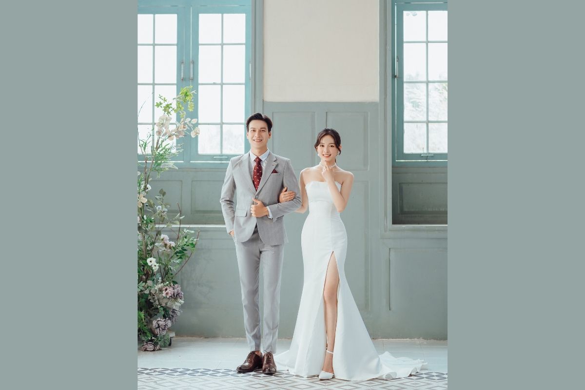 Váy cưới đuôi cá đơn giản cô dâu mặc váy quây màu trắng khoác tay chú rể đứng bên cạnh