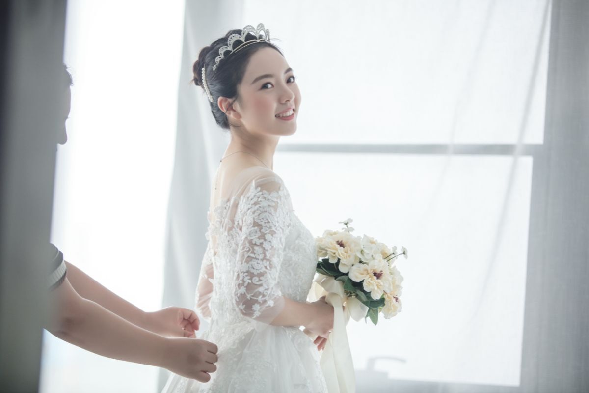 Mẫu áo váy cưới đơn giản đẹp tinh tế cô dâu đội vương miện và tay cầm bó hoa màu trắng