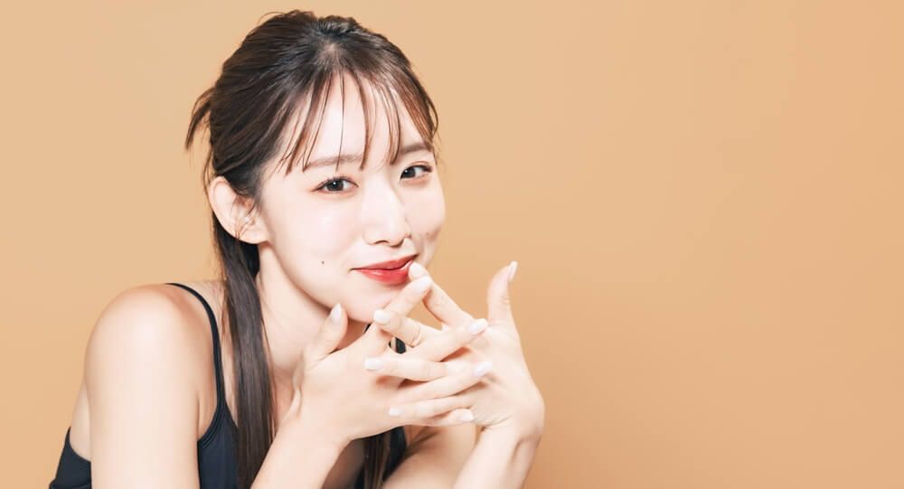 cách trị thâm môi cô gái có đôi môi tô son đỏ tươi đang cười và đan bàn tay vào nhau