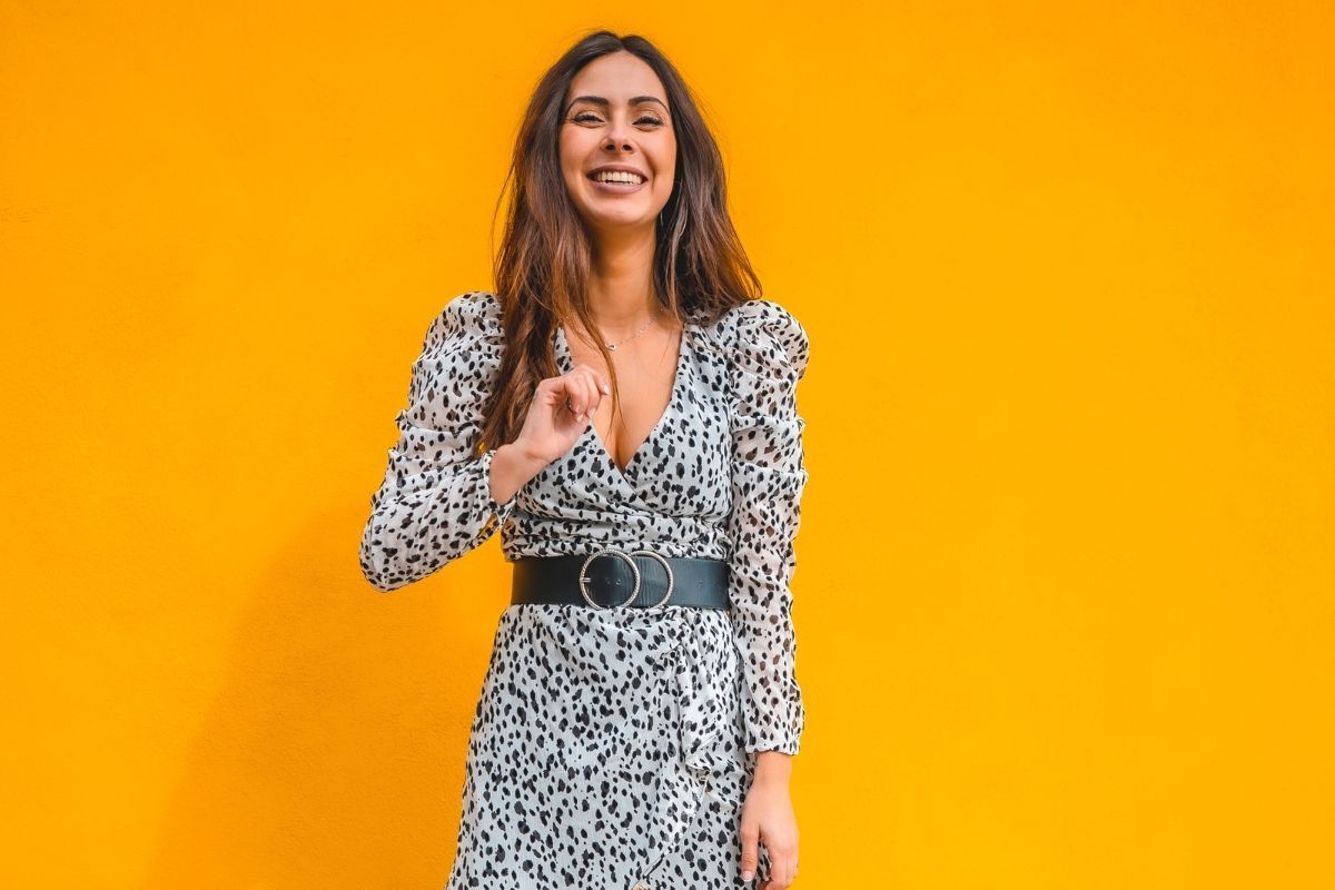 váy đi đám cưới cô gái mặc đầm vải mỏng chấm đen trên nền xám cười tươi trên nền cam