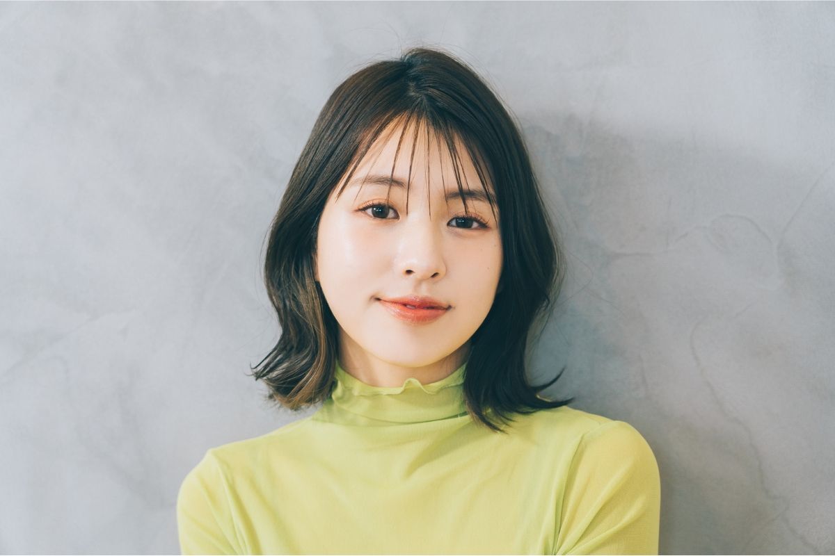 kiểu tóc uốn đuôi đẹp đến trường cô gái tóc ngắn đuôi tóc cong mặc áo xanh lá chuối cười mỉm