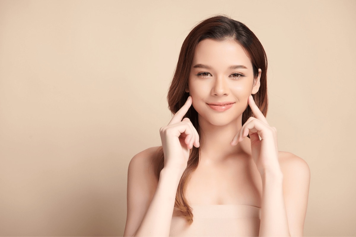 tác dụng của tinh dầu tràm trà tinh dầu tràm trà có tác dụng gì kháng khuẩn cho da cô gái đưa hai ngón tay chạm vào hai má