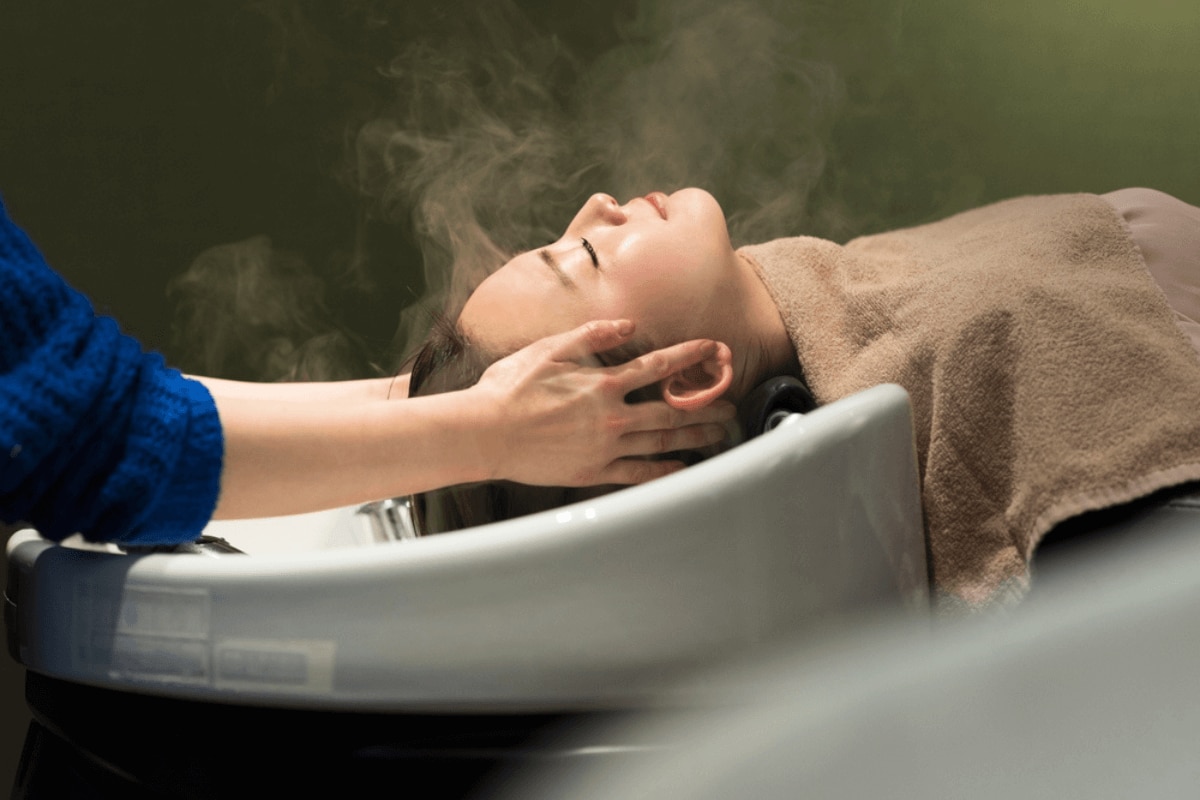 gội đầu dưỡng sinh vì sao gội đầu dưỡng sinh trở thành trào lưu cô gái đắp khăn tắm màu nâu đang được gội đầu tại salon