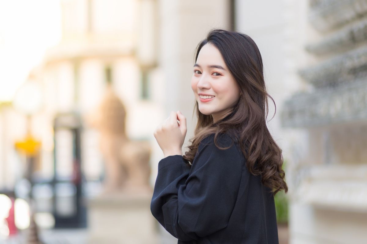 Các kiểu tóc uốn nữ đẹp cô gái mặc áo đen quay nửa mặt tóc xoăn cười tươi