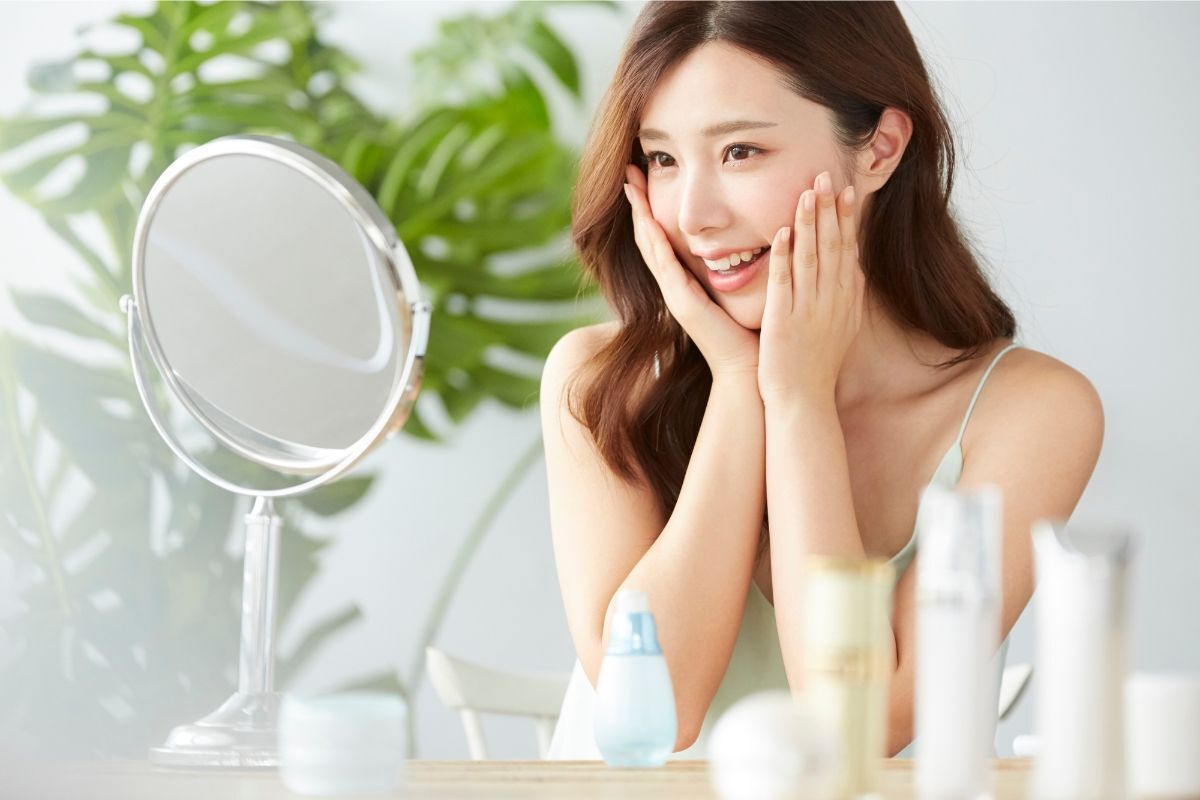 Bôi kem chống nắng đúng cách cô gái tóc xoăn dài đang soi gương