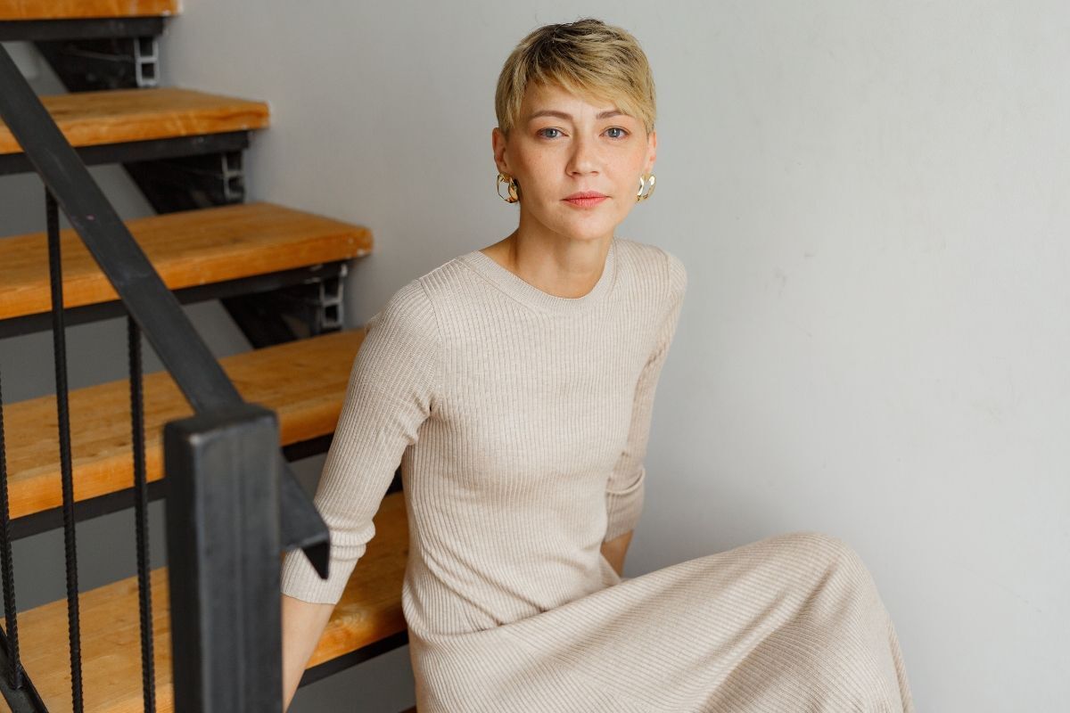 Thử ngay style tóc ngắn tomboy chất như nước cất cho bạn cô gái mặc váy len mỏng dài ngồi trên bậc cầu thang gỗ