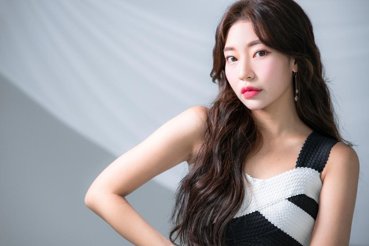 Tóc tỉa layer xoăn sóng nước cô gái mặc váy màu đen và trắng phía sau nền tường xám