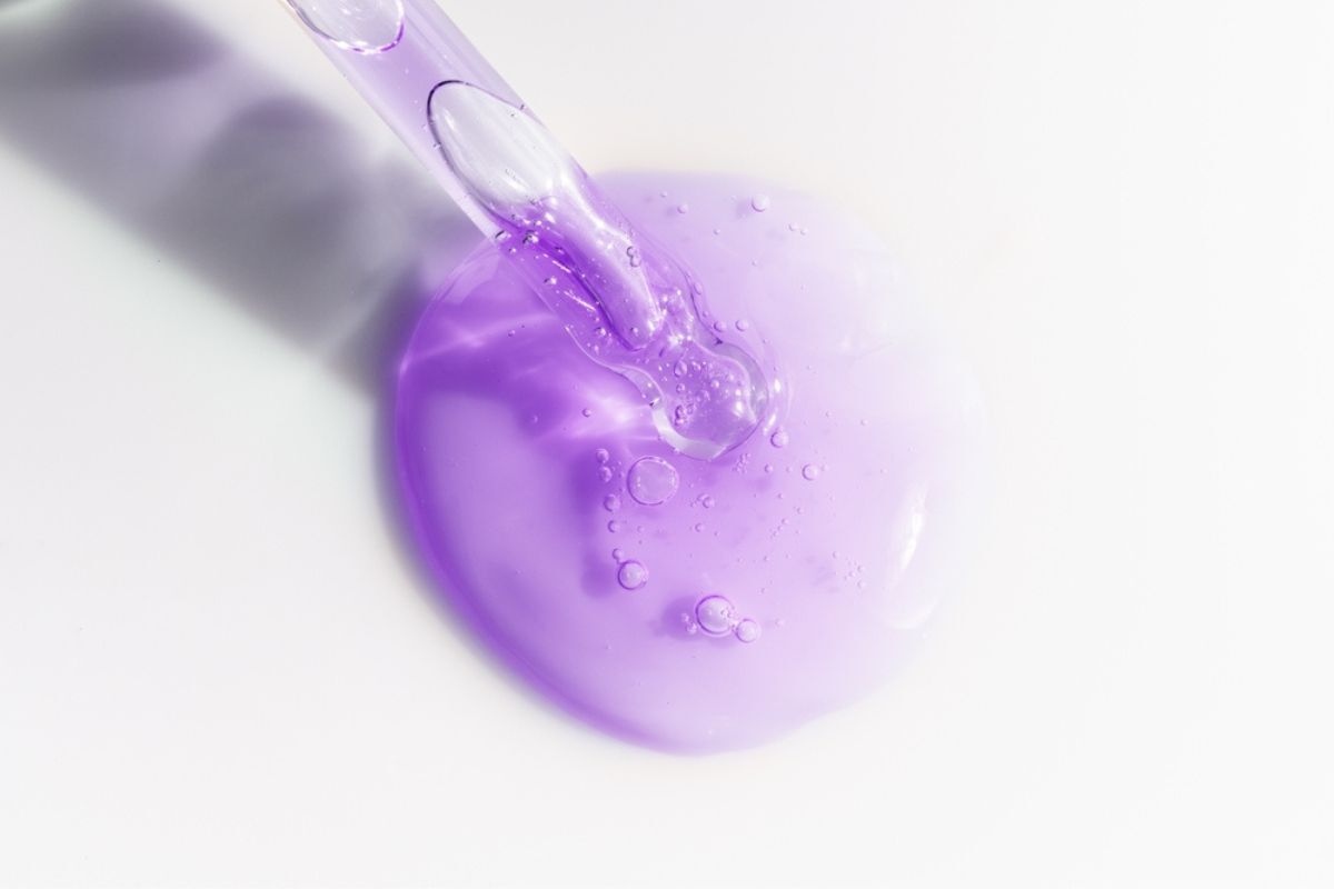 Bakuchiol hiểu hơn về phiên bản lành tính của Retinol hình ảnh chụp serum màu tím trên mặt bàn màu trắng