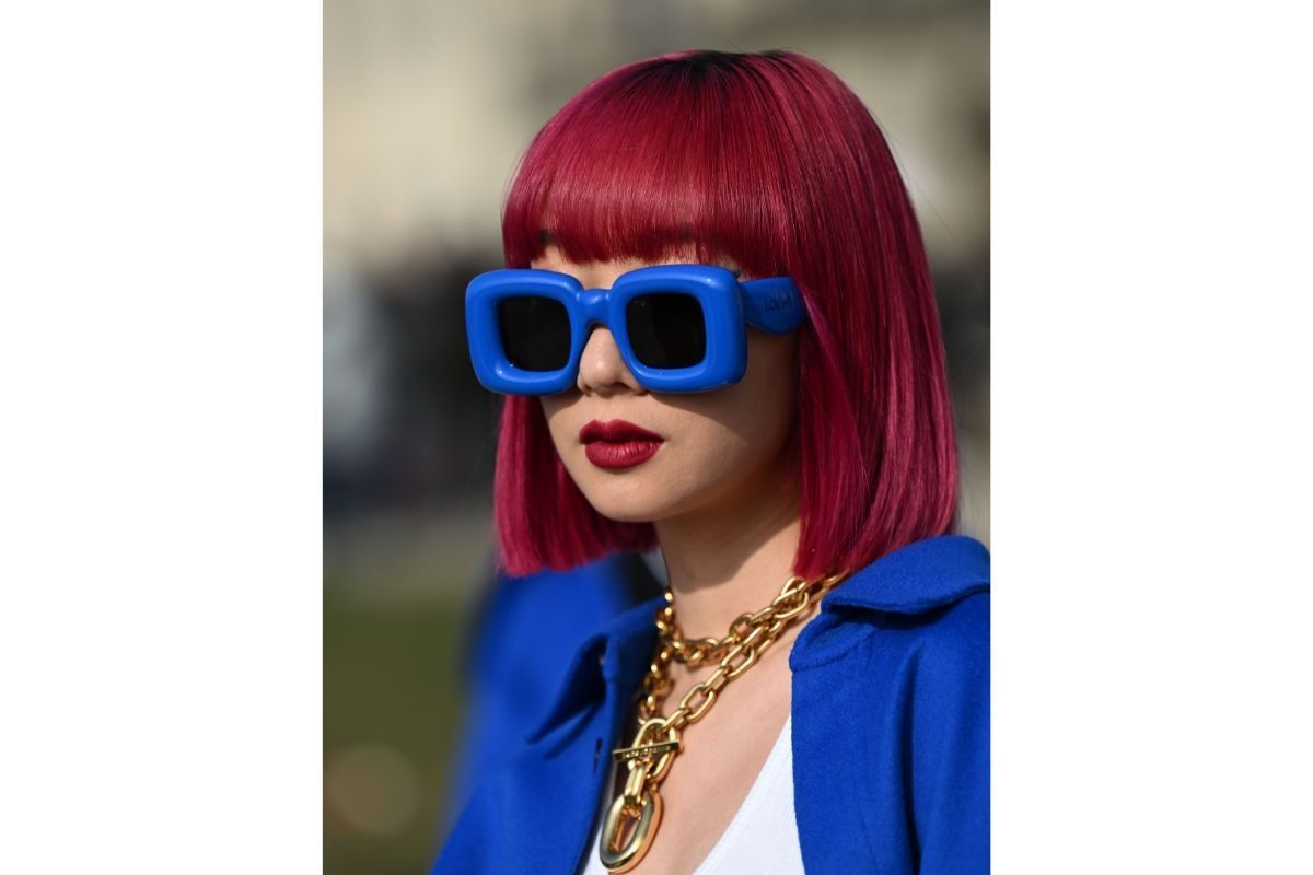 Tóc đỏ hồng cô gái đeo kính và mặc áo khoác màu xanh dương