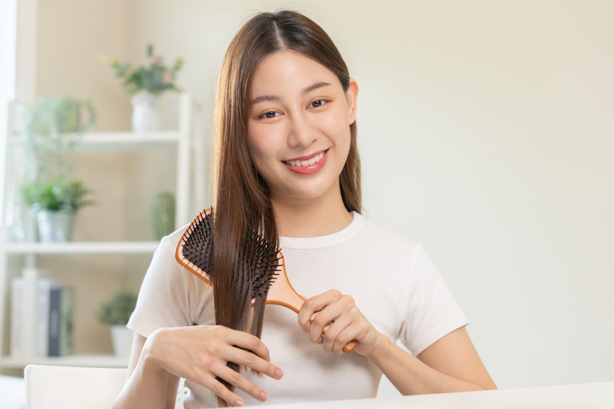 cách nhuộm tóc tại nhà đều màu cô gái đang cầm lược gỗ chải tóc