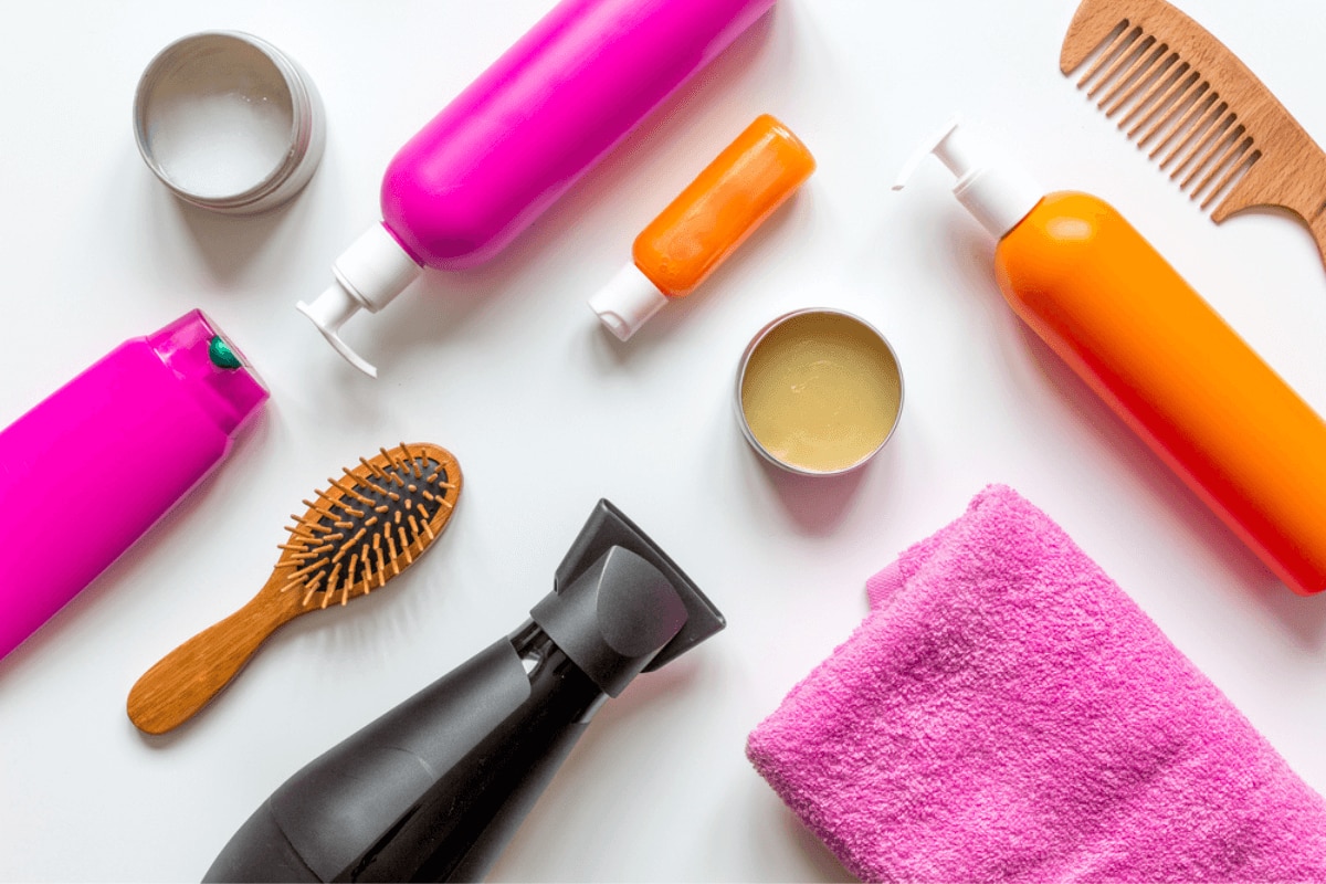 nguyên nhân rụng tóc ở nữ sử dụng sản phẩm chăm sóc tóc không phù hợp các sản phẩm và công cụ chăm sóc tóc nằm kế nhau trên nền trắng