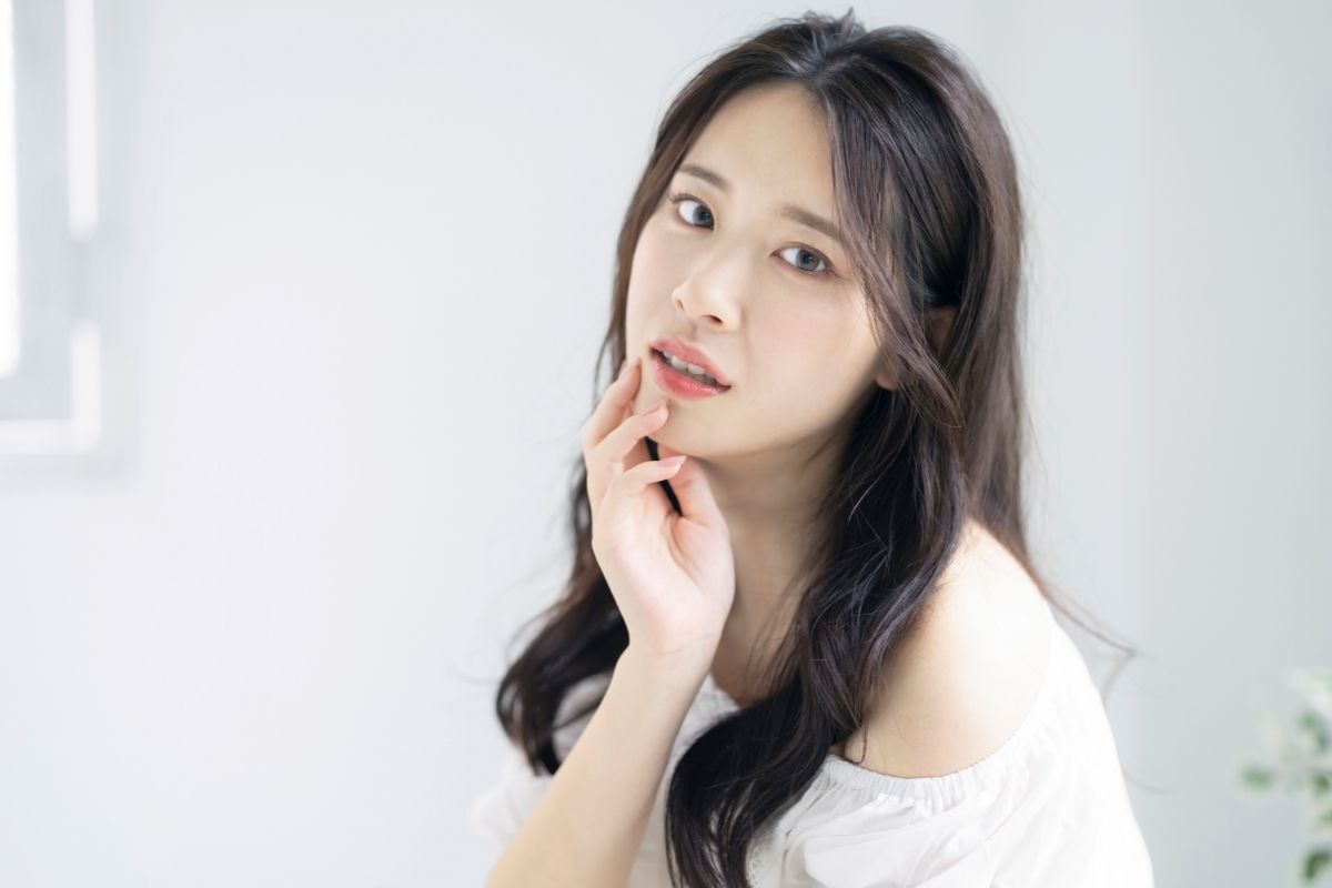 tóc layer nữ mặt dài cô gái mặc áo trắng tóc đen dài gơn sóng mái bay để tay lên miệng