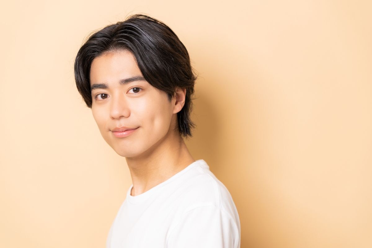 Tóc middle part chàng trai mặc áo thun trắng chụp hình trên phông nền vàng