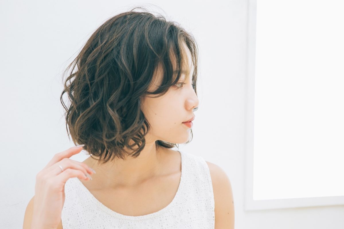 Cách cắt mái layer cô gái mặc áo trắng đang nhìn sang bên phải phía sau là ô cửa sổ hình vuông