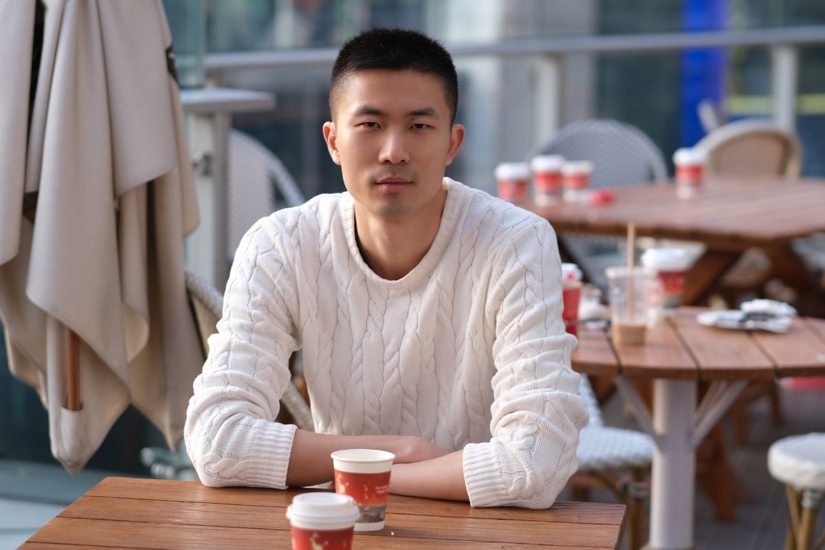 Tóc buzz cut buzz cut cổ điển chàng trai mặc áo len màu trắng chống tay lên bàn