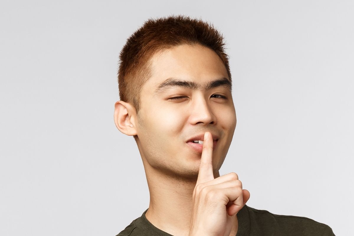 Tóc buzz cut Burr buzz cut chàng trai đưa ngón tay lên miệng nháy mắt