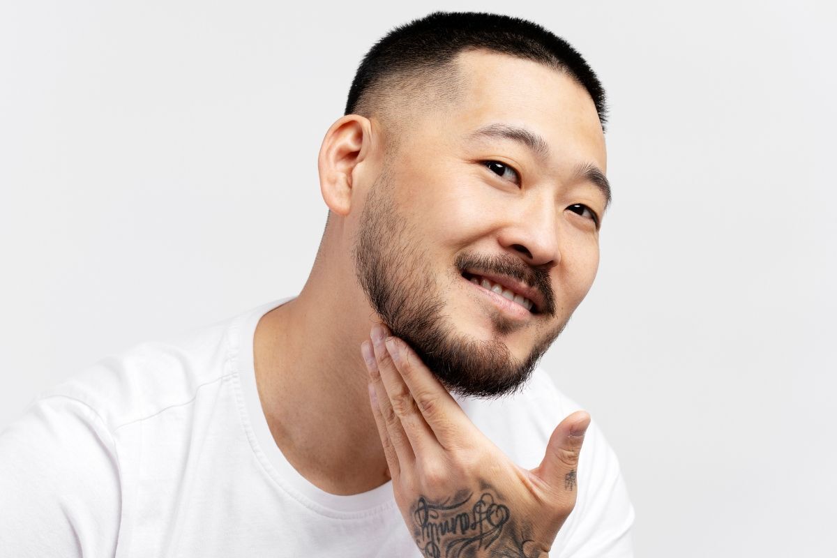 Tóc buzz cut kiểu tóc high and tight chàng trai nghiêng mặt tay chạm vào râu