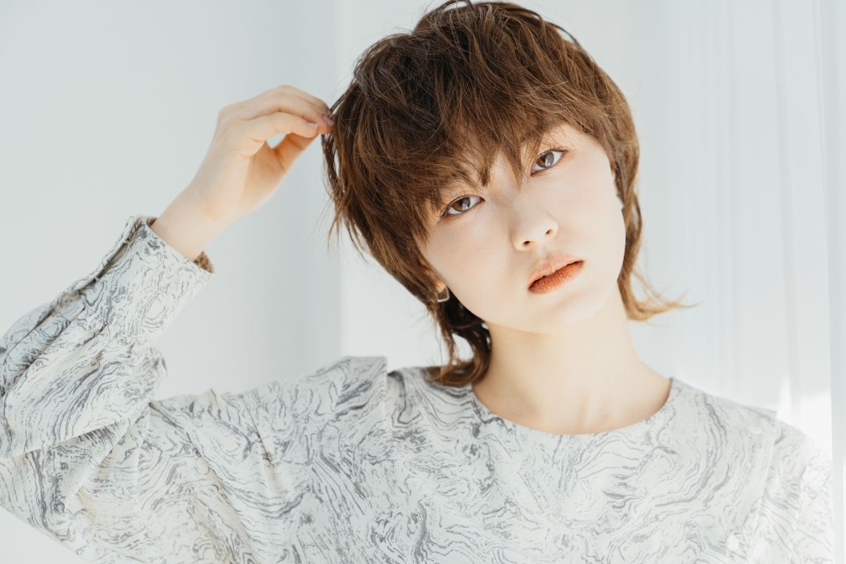 Tóc mullet layer nữ tomboy cô gái đang nghiêng đầu và tay chạm vào tóc