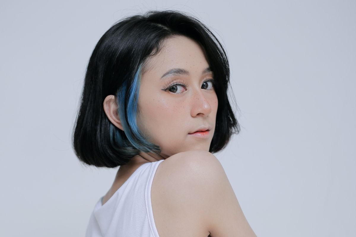 Tóc nhuộm giấu màu xanh dương cô gái mặc áo ba lỗ trắng đang quay đầu lại nhìn