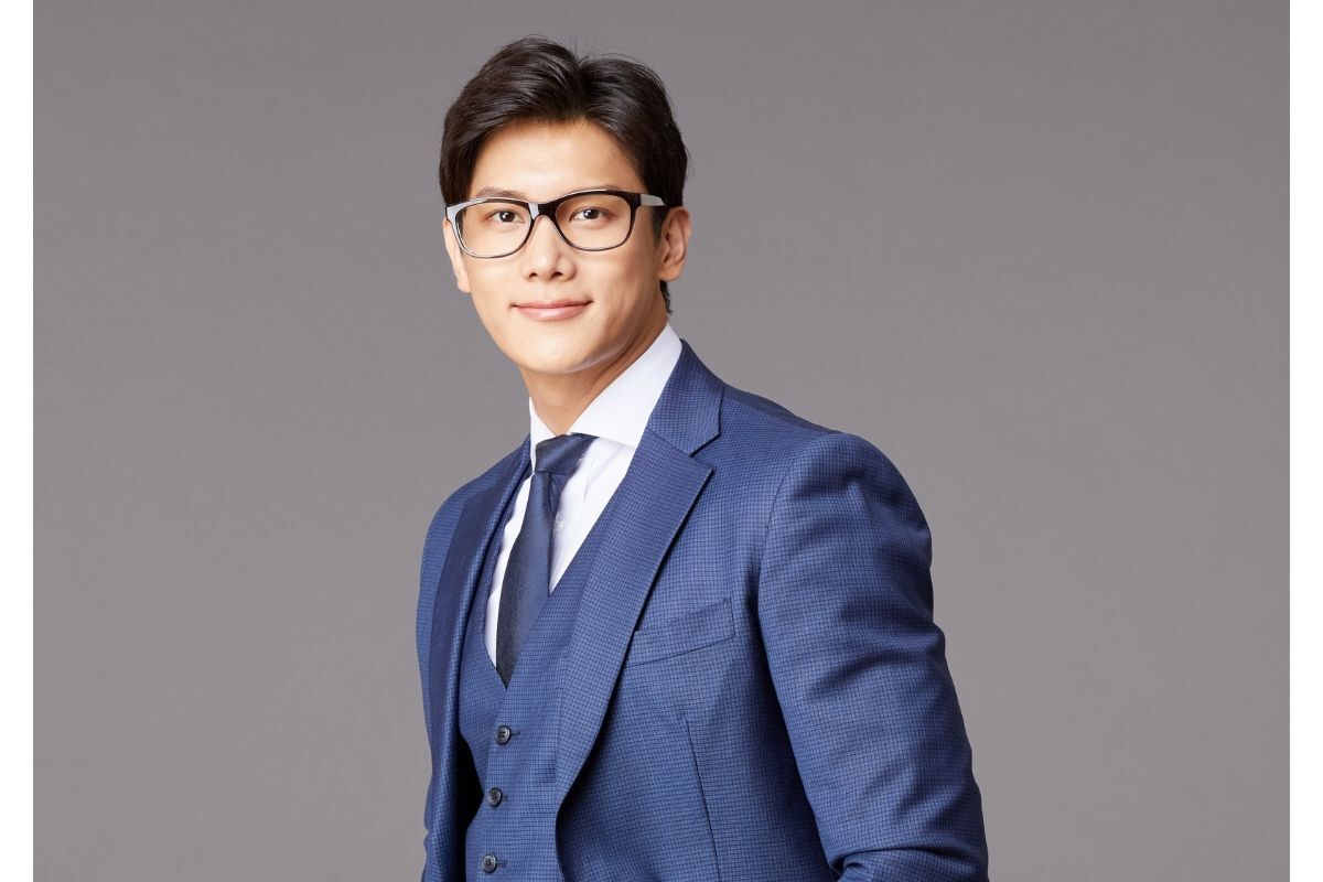 thời trang nam cao cấp chàng trai mặc bộ suit màu xanh dương đeo kính đen chụp trên nền xám
