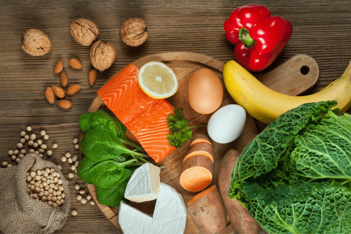 nguyên nhân rụng tóc ở nữ phương pháp cải thiện bổ sung chất dinh dưỡng cá hồi trứng khoai lang chuối và các loại hạt hạnh nhân và óc chó trên thớt gỗ