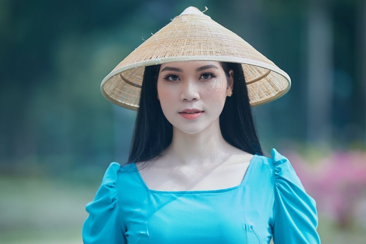 Cô gái mặc áo dài cổ vuông màu xanh dương và đội nón lá