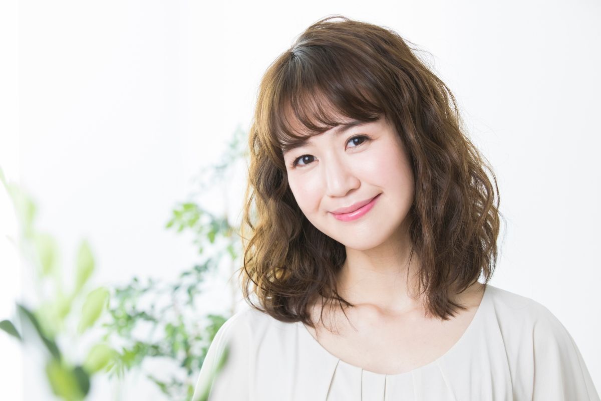 Tóc lỡ tóc lỡ uốn gợn sóng cô gái mặc áo màu be phía sau là cây màu xanh là bị làm mờ