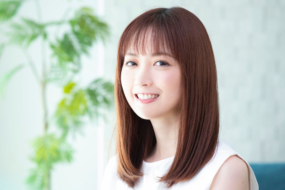 Tóc lỡ tóc lỡ ngang vai thẳng mái thưa cô gái mỉm cười phía sau là chậu cây xanh bị làm mờ