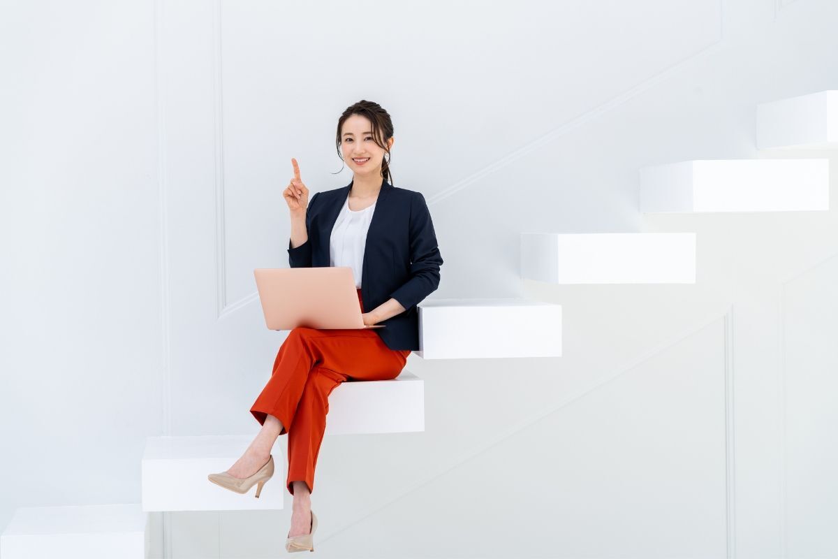 Thời trang công sở cô gái mặc áo vest màu đen và quần màu đỏ ngồi trên bậc cầu thang