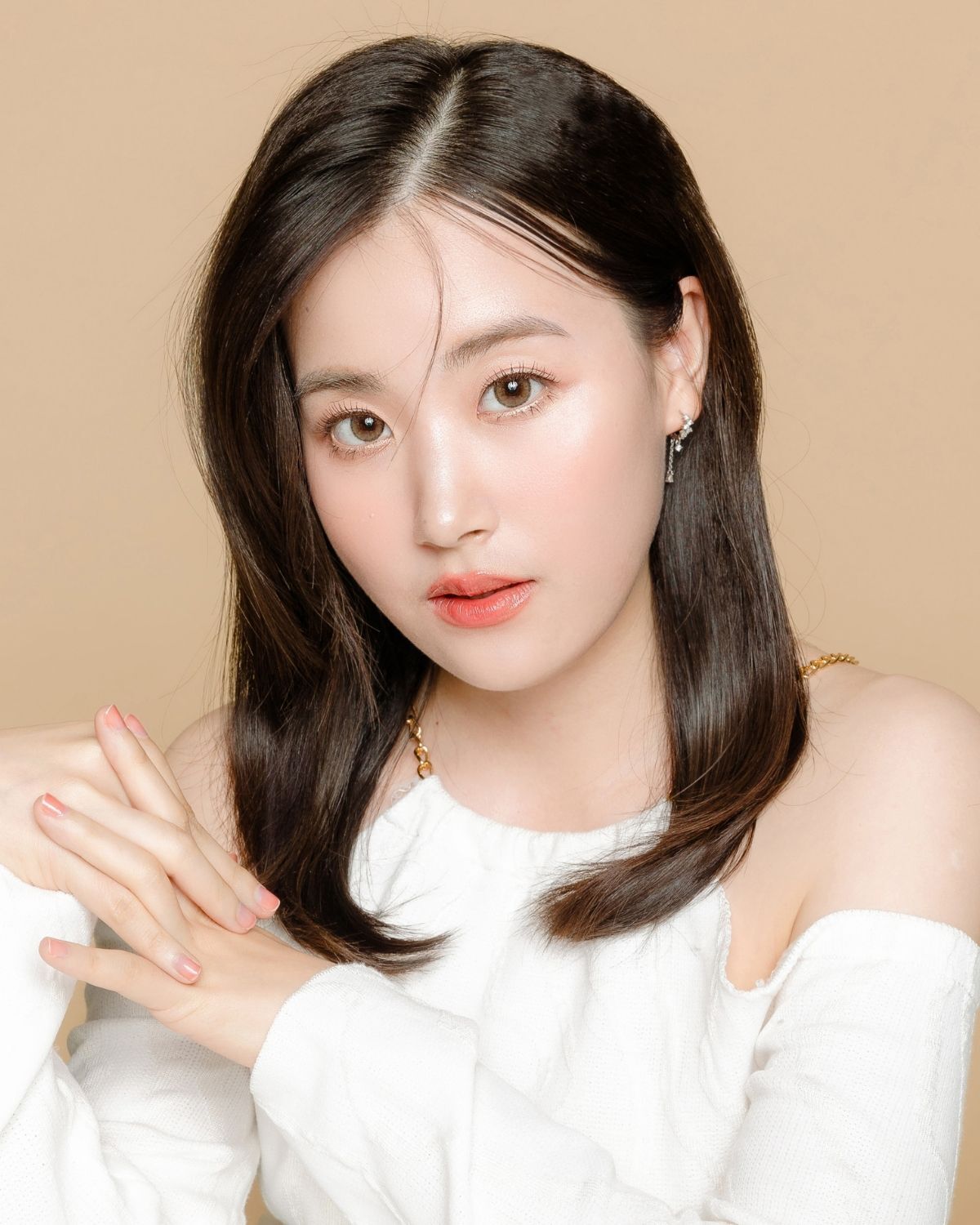 Tóc lỡ kiểu ép cụp tóc lỡ cô gái đan hai bàn tay vào nhau chụp trên nền màu be