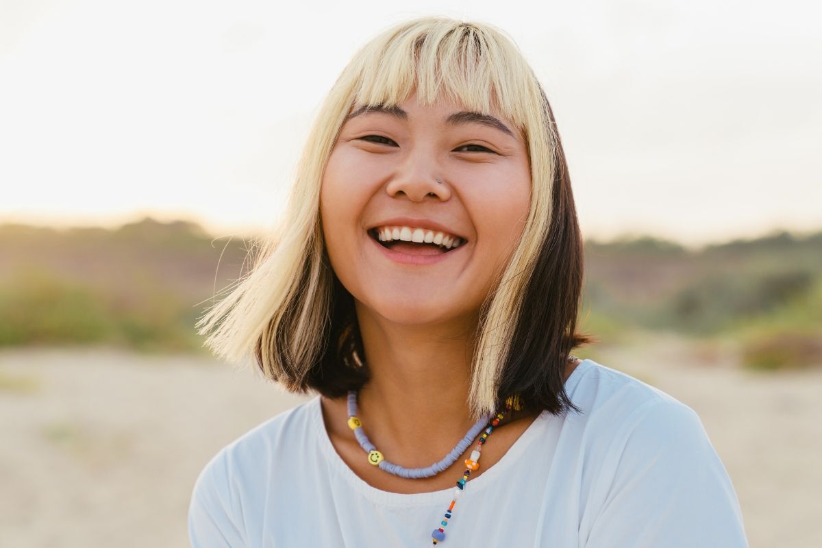 Tóc lỡ kiểu tóc lỡ nhuộm cá tính cô gái mặc áo thun trắng cười tươi nền phía sau bị làm mờ