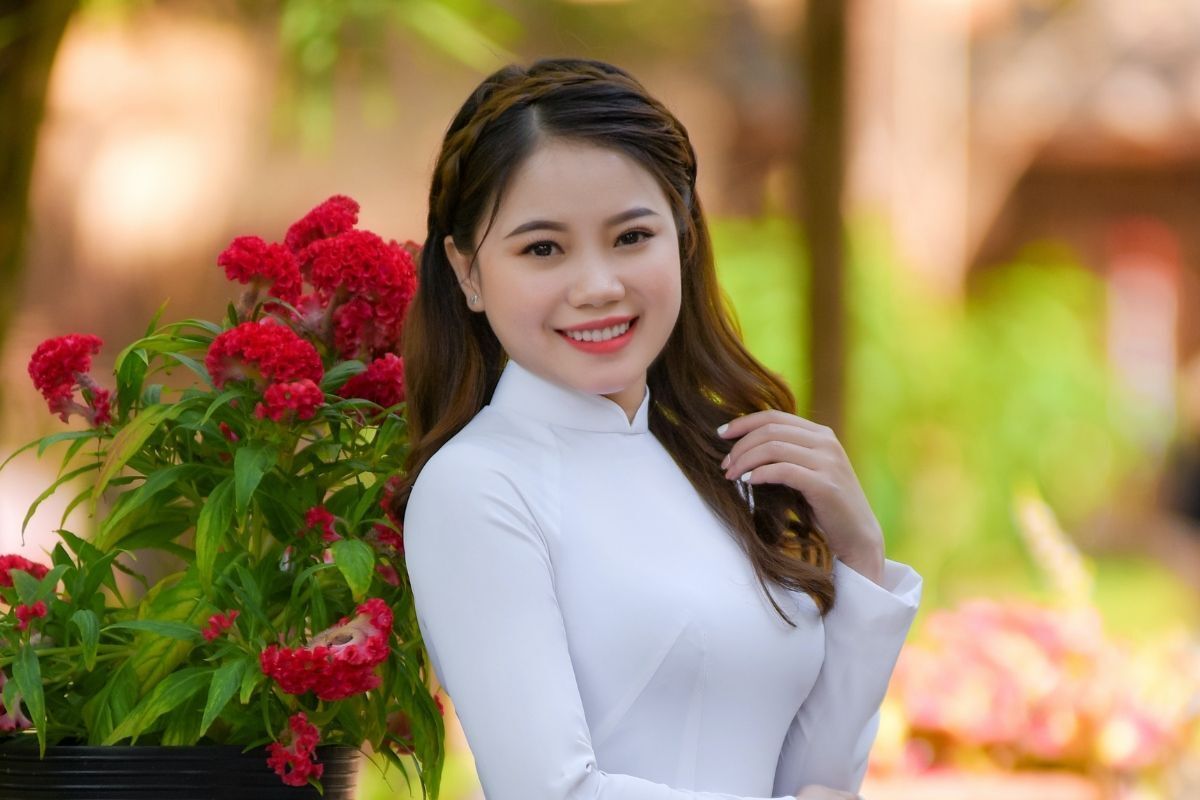 Tết tóc mặc áo dài cô gái tết tóc nửa đầu đang cười tươi nhìn vào ống kính