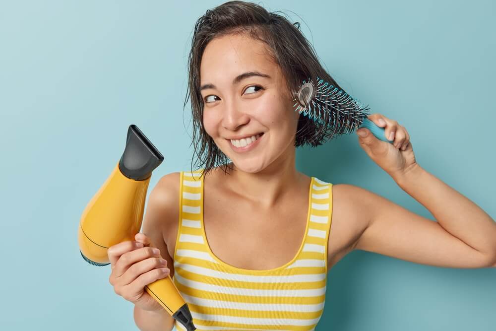 cách sấy tóc phồng cách làm tóc phồng với lược tròn cô gái có mái tóc ướt đang dùng lược tròn và máy sấy