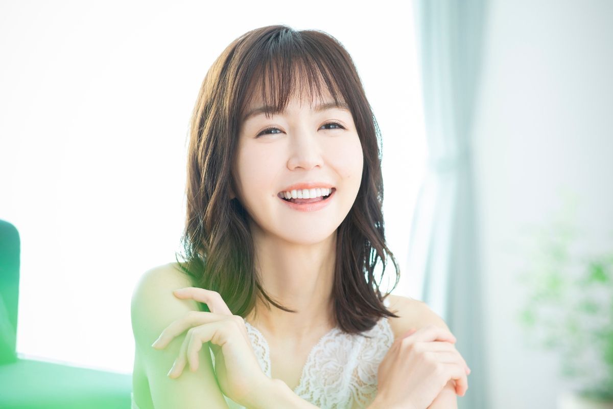 Cô gái cười tươi để kiểu tóc ngang vai Hàn Quốc với hai tay chạm lên vai ảnh chụp trong phòng