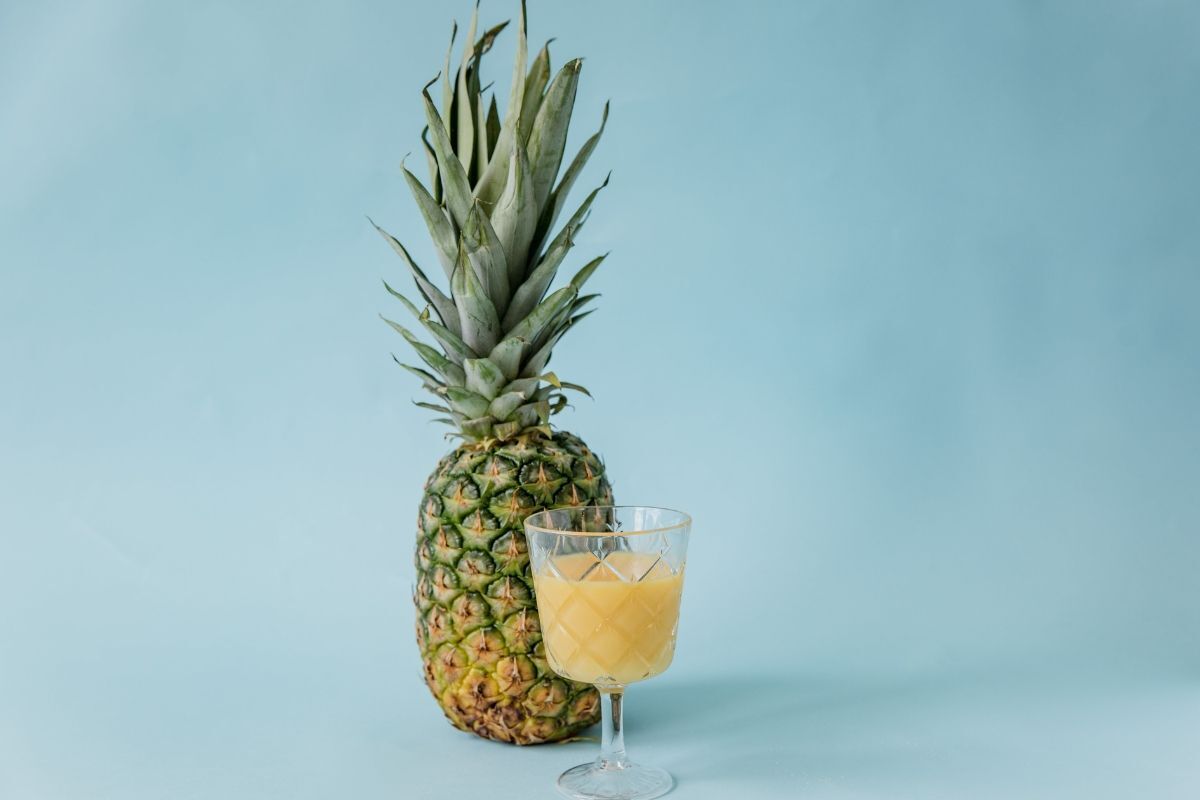 Quả dứa và ly nước trên nền xanh dương nhạt