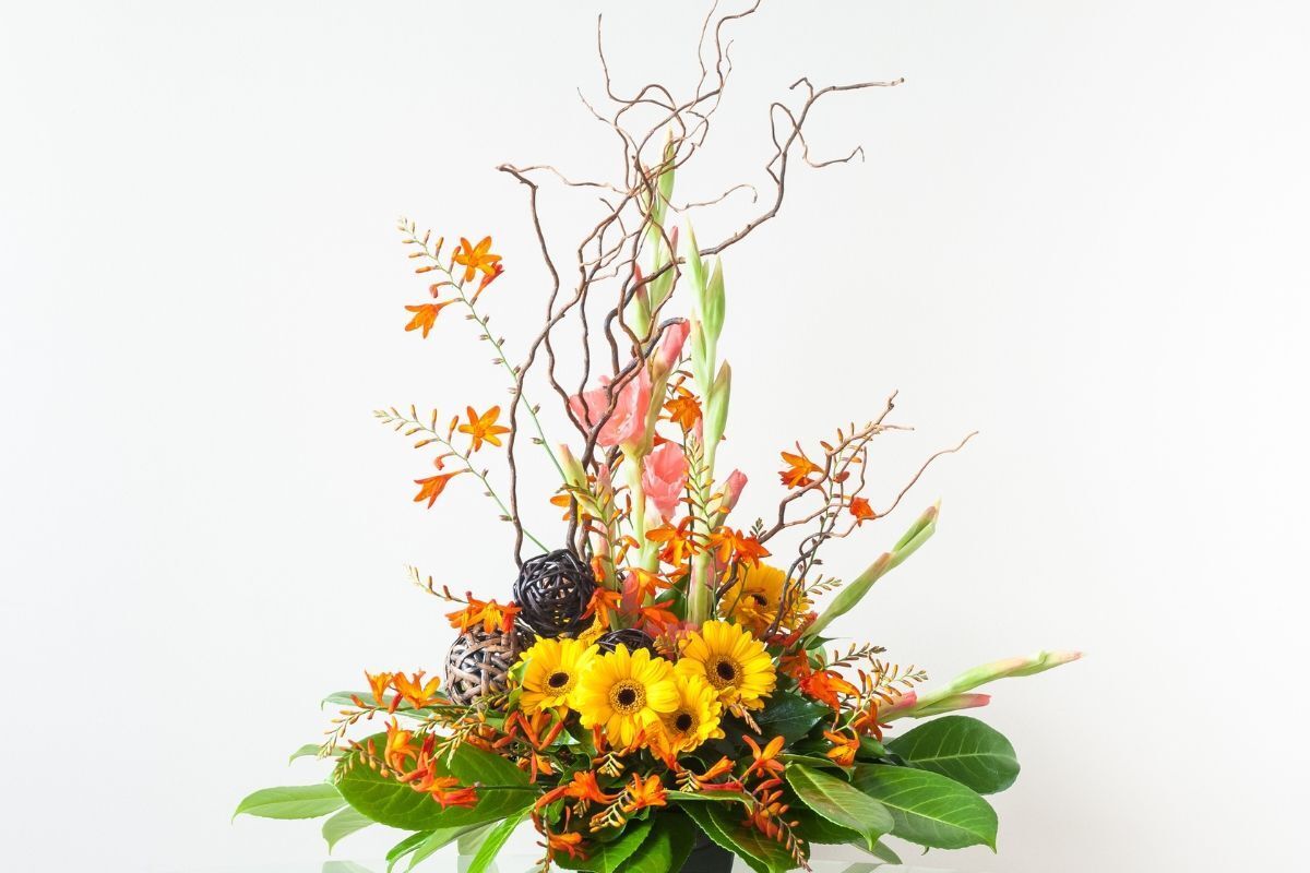 cắm hoa nghệ thuật bình hoa có hoa hướng dương ở giữa cùng các chiếc lá phía dưới