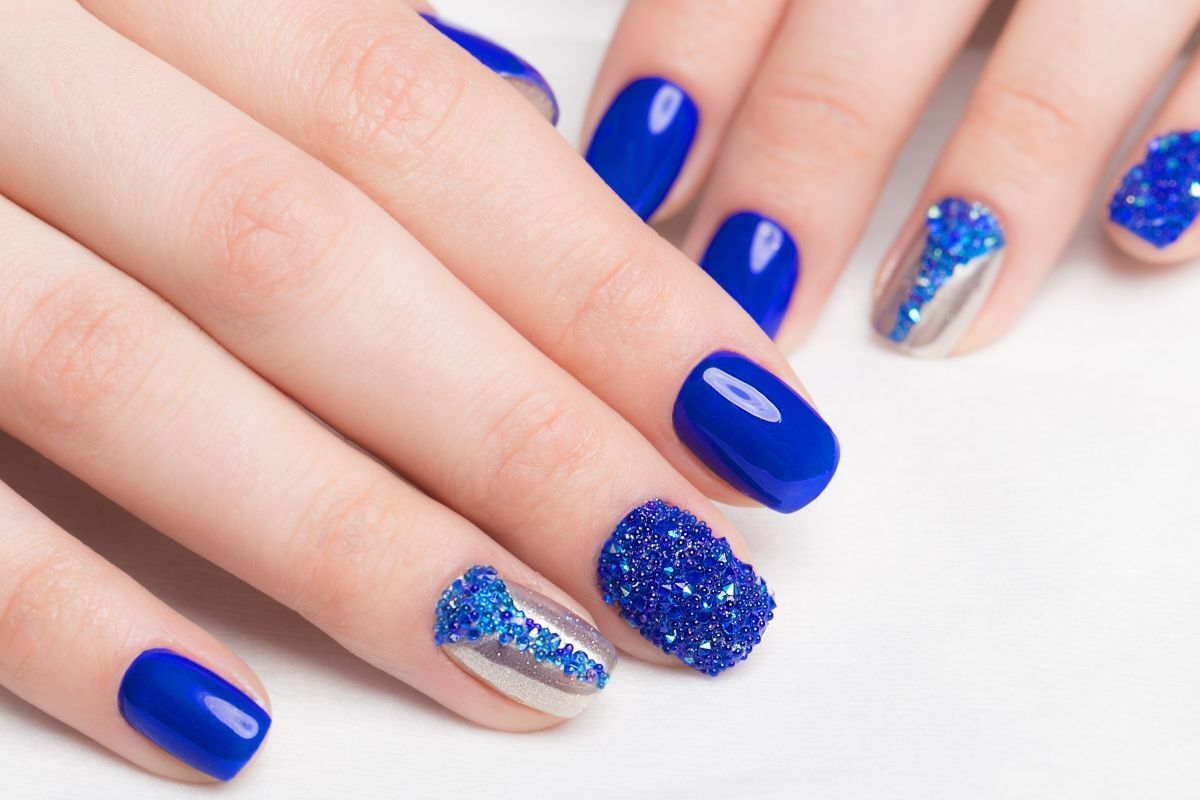Nail đẹp màu xanh dương đính đá đặt trên nền trắng