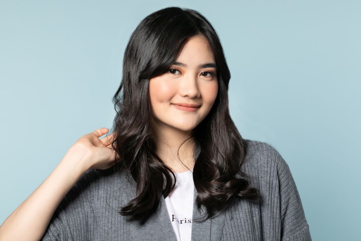 Tóc mái bay là gì cô gái mặc áo len xám tóc đen mỉm cười