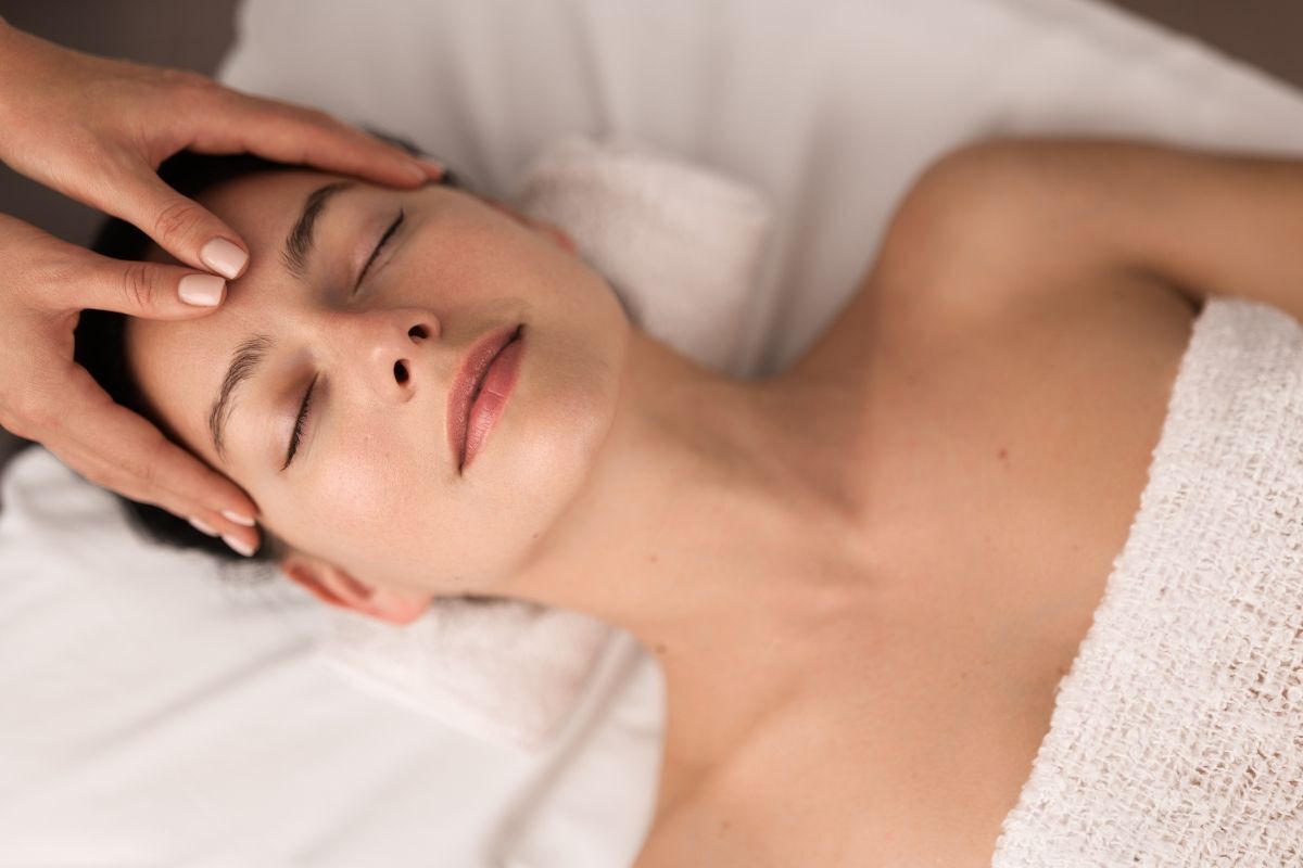 cách massage cho mắt cô gái nằm trên giường đang được massage