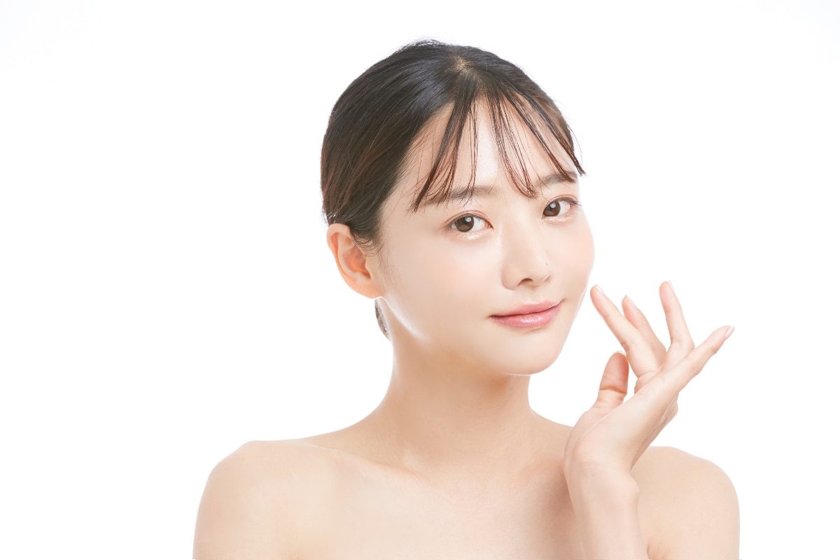 Cô gái chạm tay lên má sau khi điều trị sợi bã nhờn