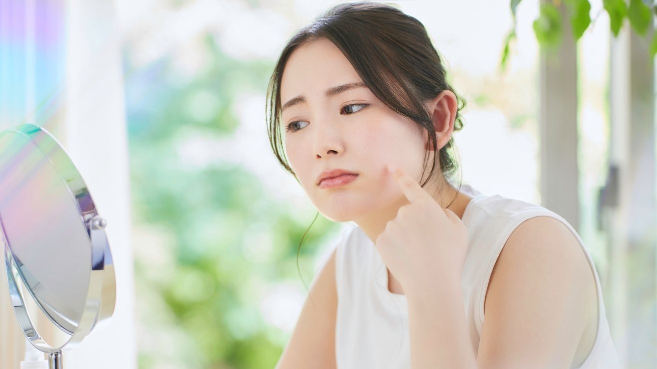 Cô gái có da mặt bị khô đang soi gương 