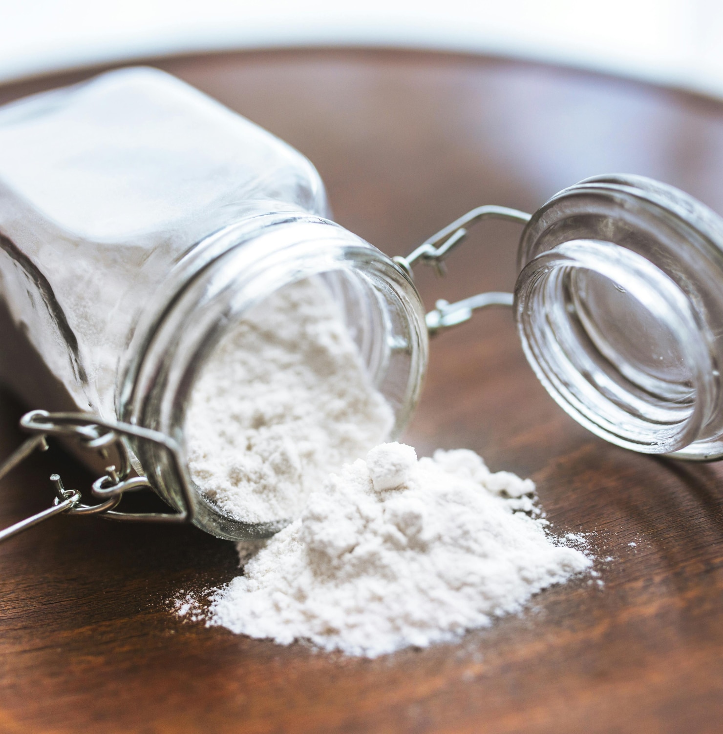 cách trị thâm nách cách làm nách hết thâm bằng baking soda hũ thuỷ tinh đựng baking soda màu trắng đổ trên bàn