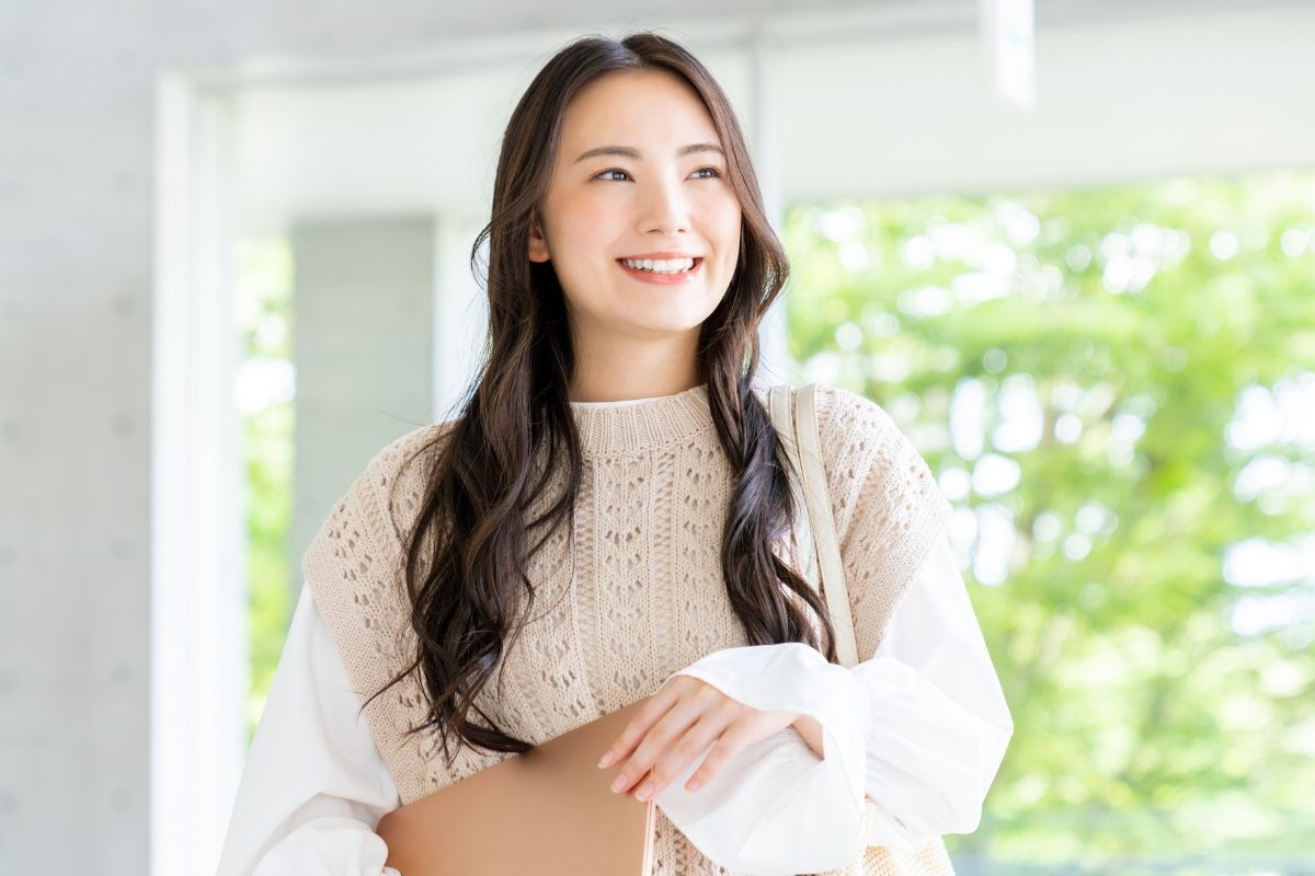 Cô gái có gương mặt hình chữ nhật và mái tóc xoăn lơi dài đang cầm tập tài liệu