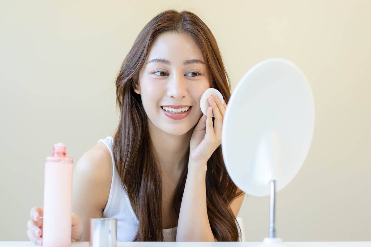 skincare cho da dầu mụn cô gái vừa soi gương vừa thoa toner cho da dầu mụn