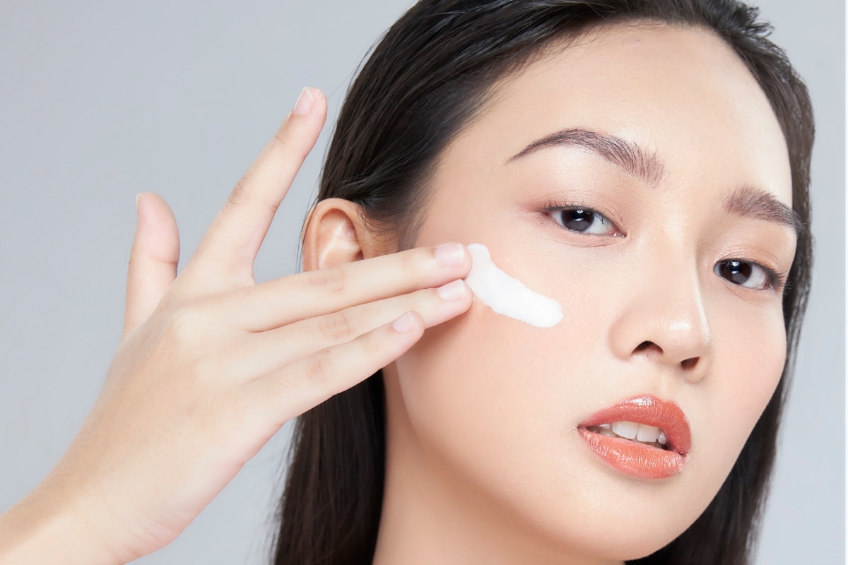skincare cho da dầu mụn cô gái thoa kem dưỡng ẩm cho da dầu mụn lên má