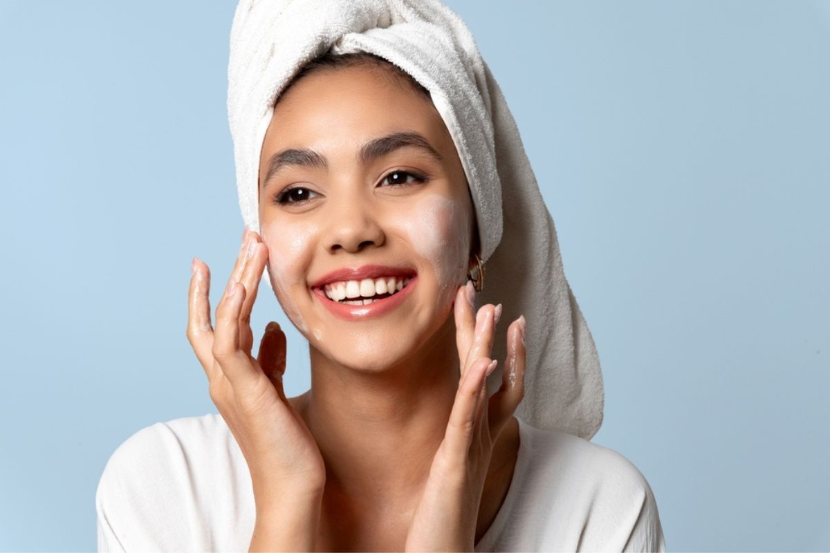 chườm đá lên mặt làm sạch da mặt cô gái quấn khăn tắm trên đầu đang xoa bọt rửa mặt