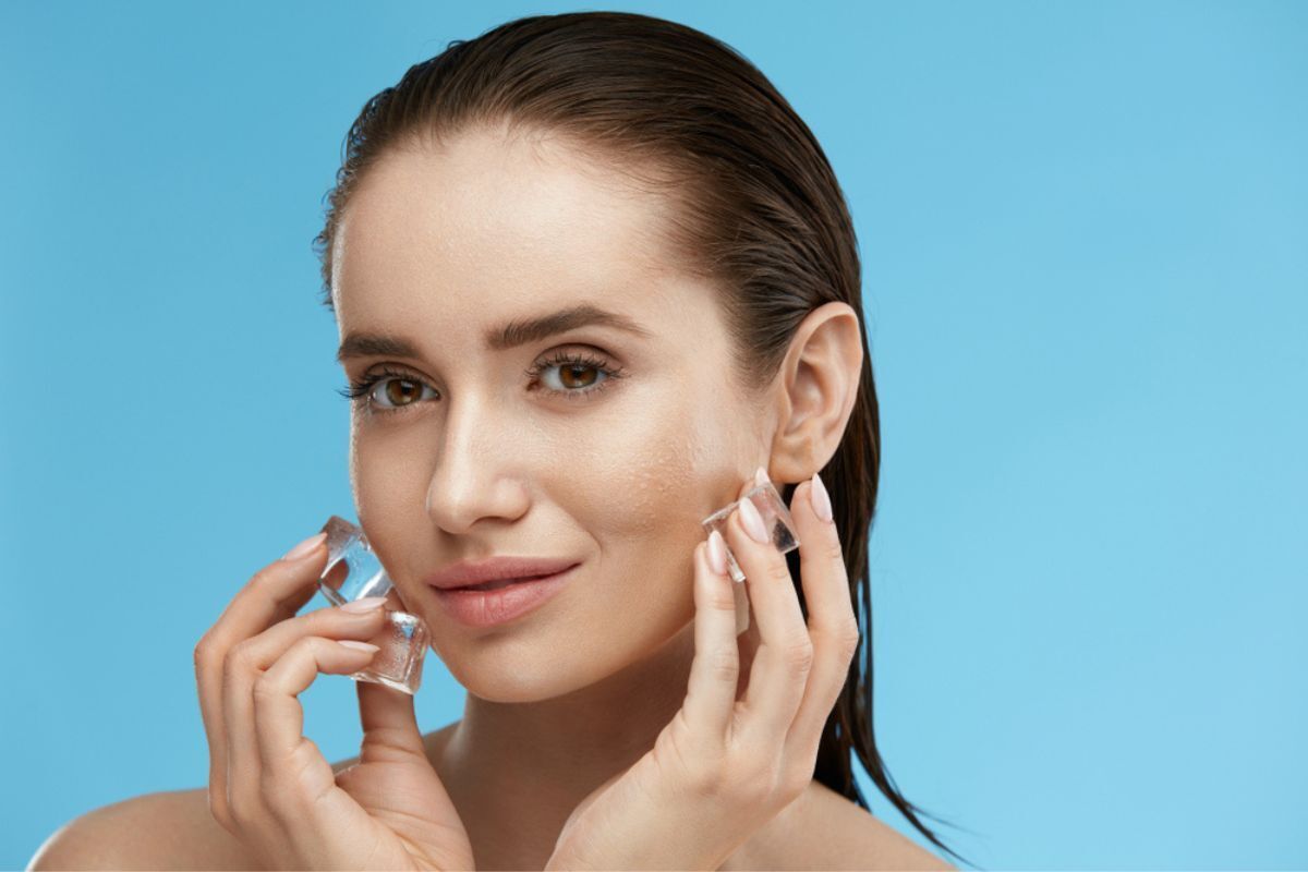 chườm đá lên mặt cô gái đang chườm đá lên mặt phía sau phông nền màu xanh dương
