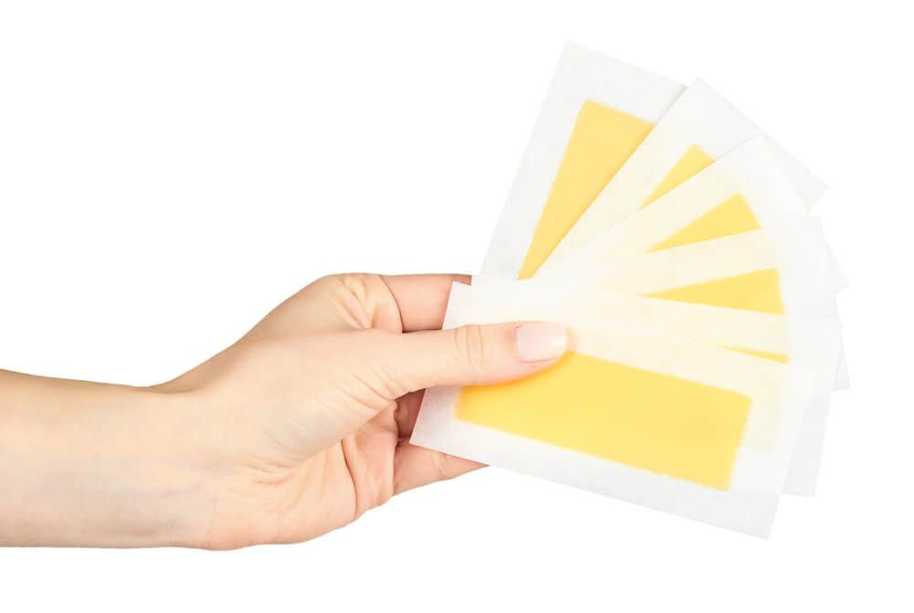 cách wax lông tại nhà cách wax lông tại nhà bằng wax lạnh bàn tay phụ nữ cầm các miếng wax lông màu vàng